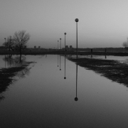 Black and white flooded sidewalk with street lamp along the way