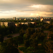 A higher vantage point on a park with the sun shining from a low angle, city center and clouds on the background