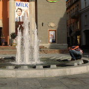 A man fishing coins from the fountain in front of an old cinema building
